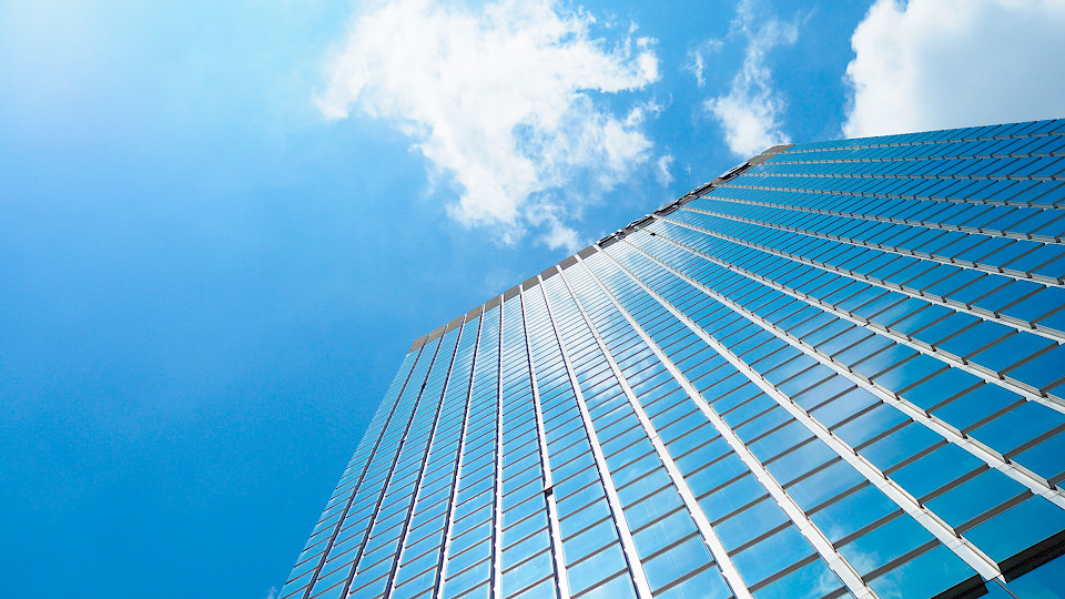 A skyscraper framed from below, with clouds in a blue sky
